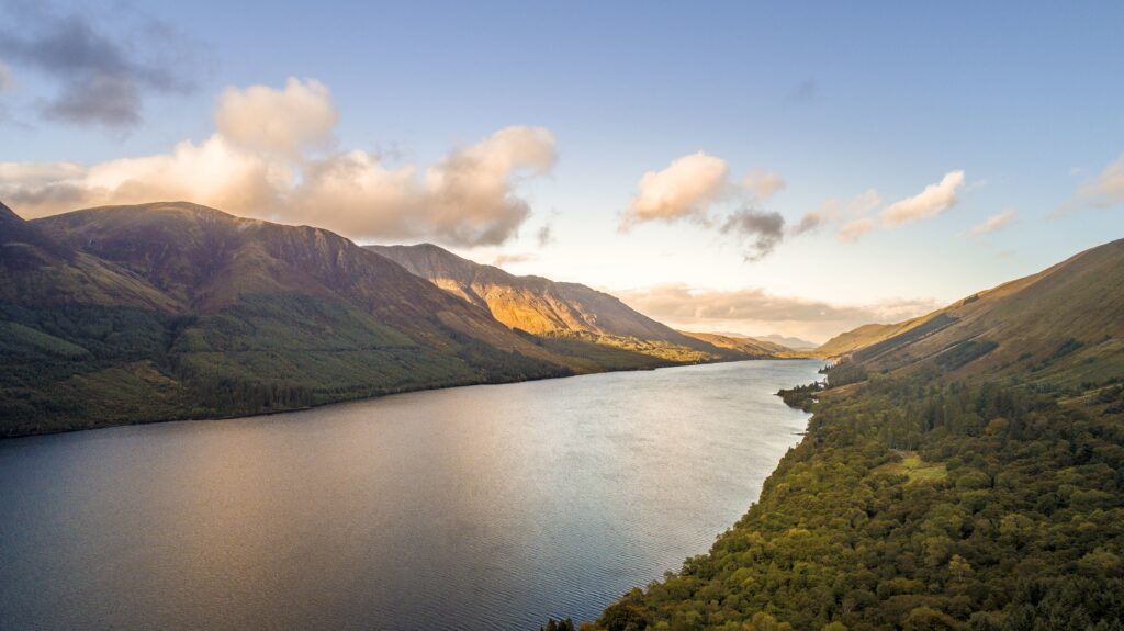Aerial shot of Loch Ness lake in Scotland captured by a drone on a clear day with some clouds appearing over head