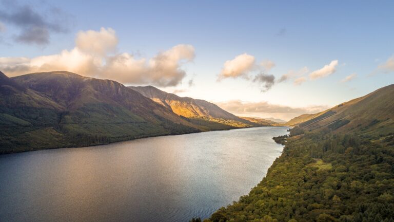 Aerial shot of Loch Ness lake in Scotland captured by a drone on a clear day with some clouds appearing over head Aerial shot of Loch Ness lake in Scotland captured by a drone on a clear day with some clouds appearing over head