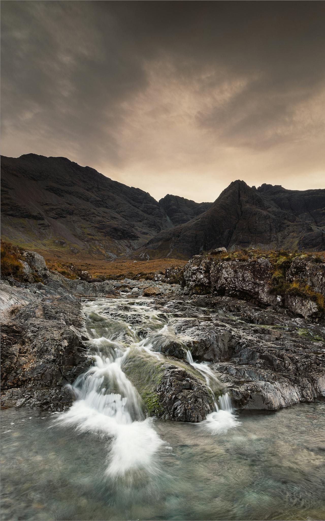 Mystical waterfall at Fairy Pools in Scotland with dramatic sky.