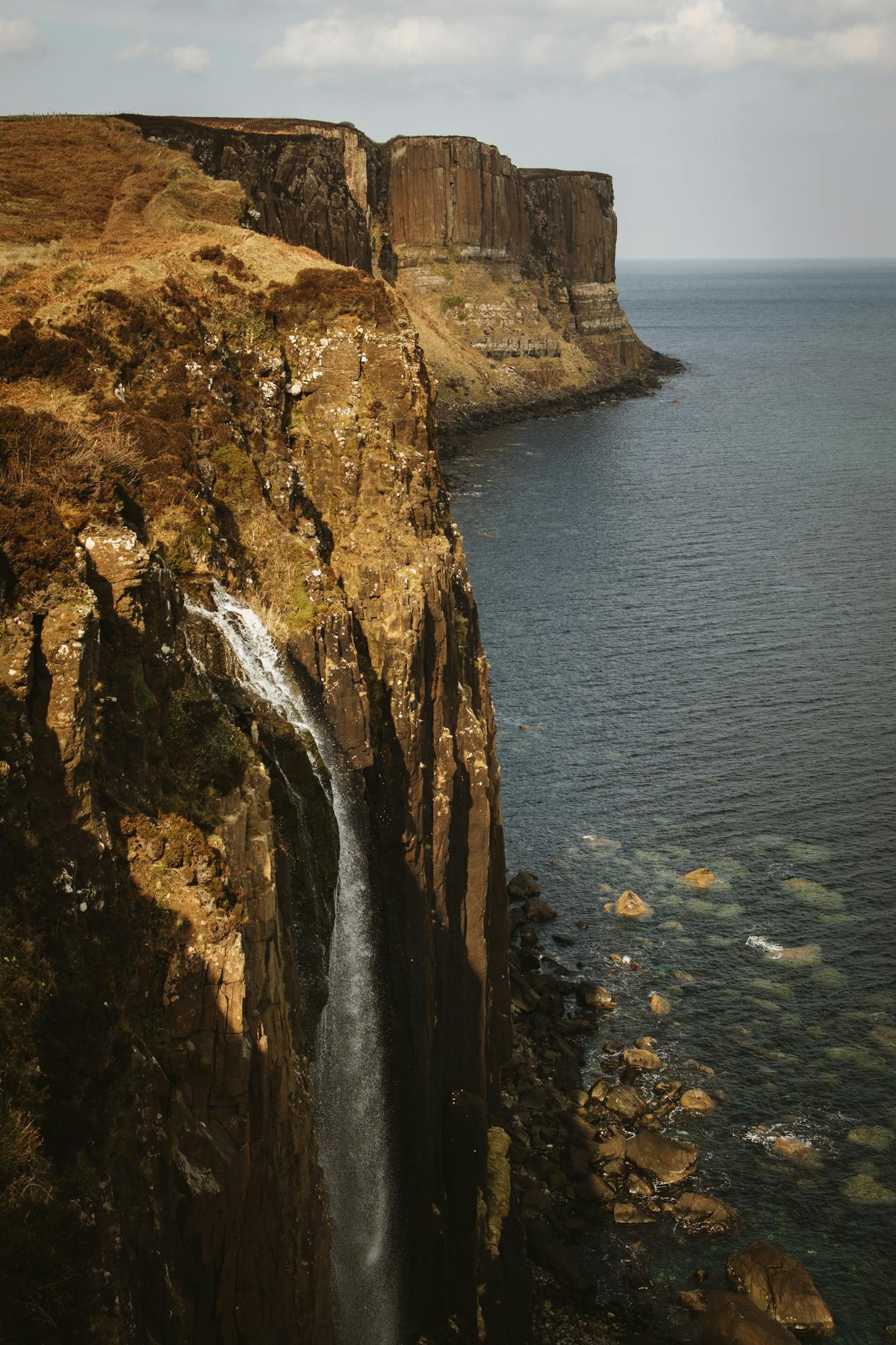 Stunning view of Mealt Falls cascading over Kilt Rock into the ocean on the Isle of Skye, Scotland.