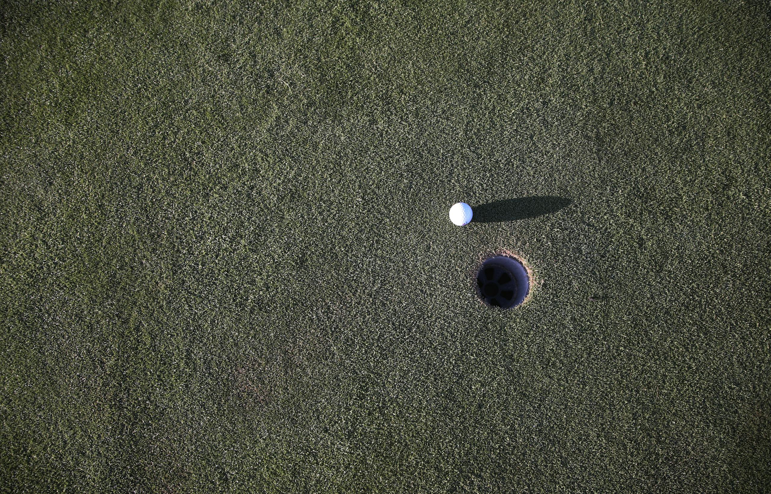 Close-up shot of a golf ball near the hole on a manicured golf course green.